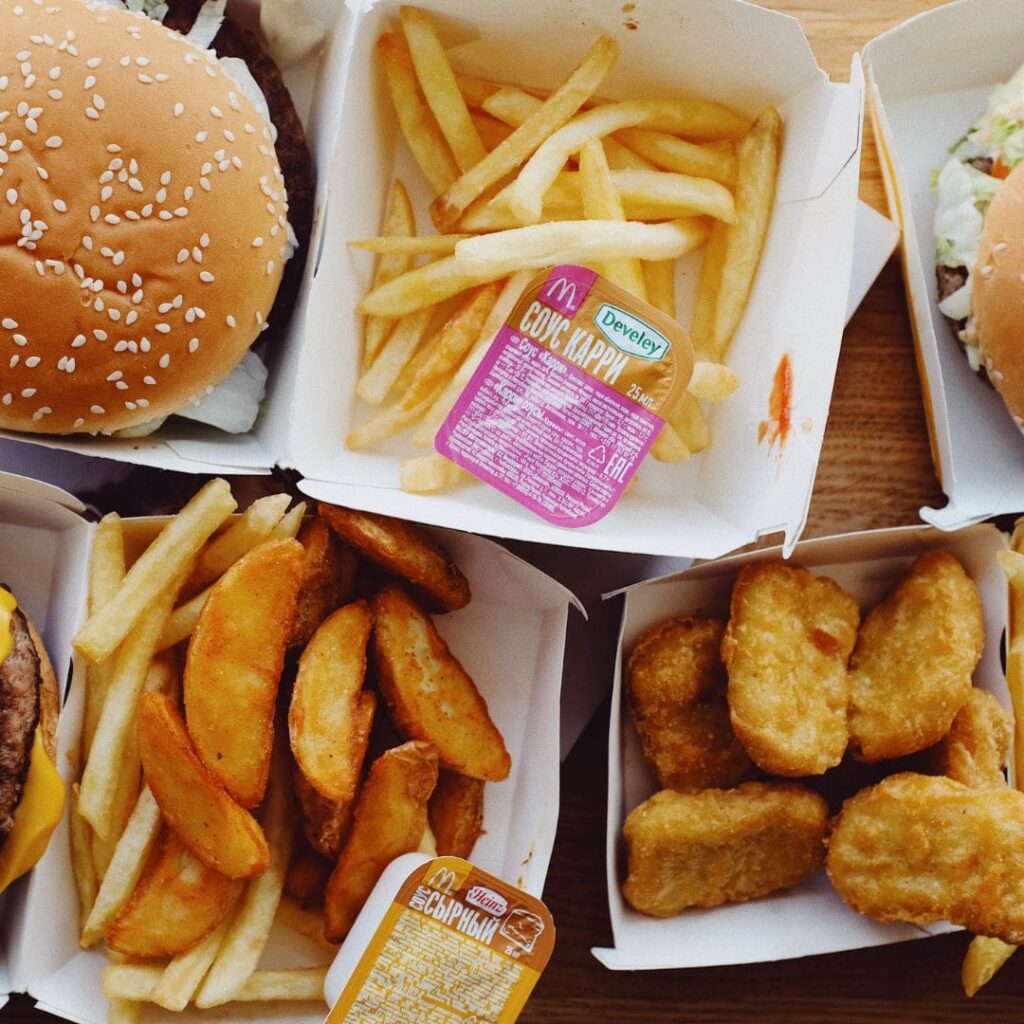 A top-down view of fast food items including burgers, fries, potato wedges, and chicken nuggets.