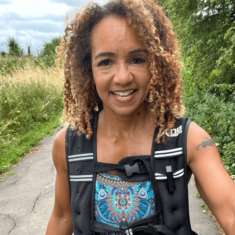 Melissa Neill smiling while walking outdoors wearing a weighted vest.